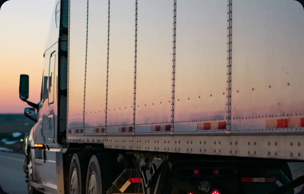 A semi-truck trailer on the highway at sunset