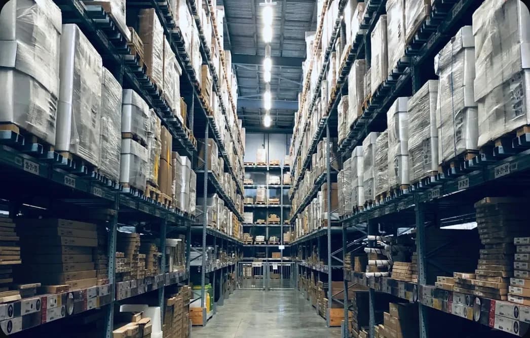 A long warehouse aisle lined with shelves of boxed spare parts