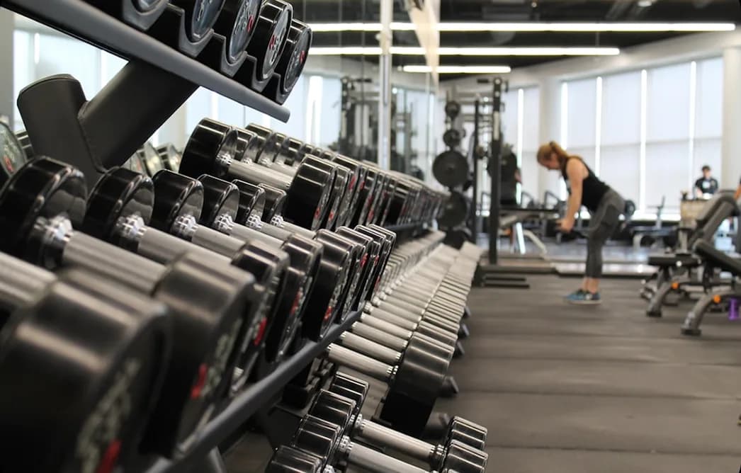 A rack of dumbbells in a gym with a member training in the background