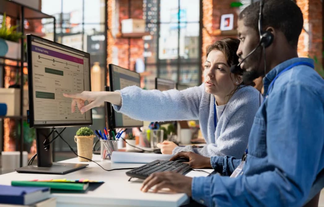 Two customer success agents collaborating at a shared support desk